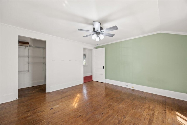 unfurnished bedroom with hardwood / wood-style floors, a closet, crown molding, baseboards, and vaulted ceiling