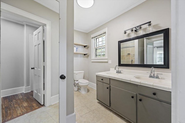 bathroom featuring ornamental molding, toilet, baseboards, and a sink