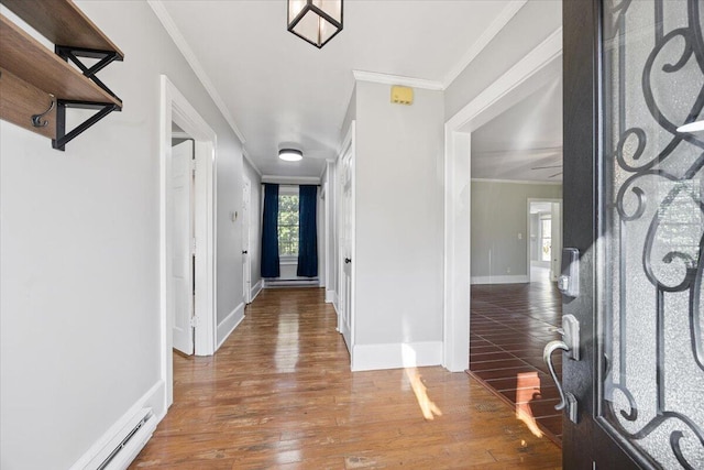 foyer entrance featuring a baseboard heating unit, crown molding, baseboards, and wood finished floors