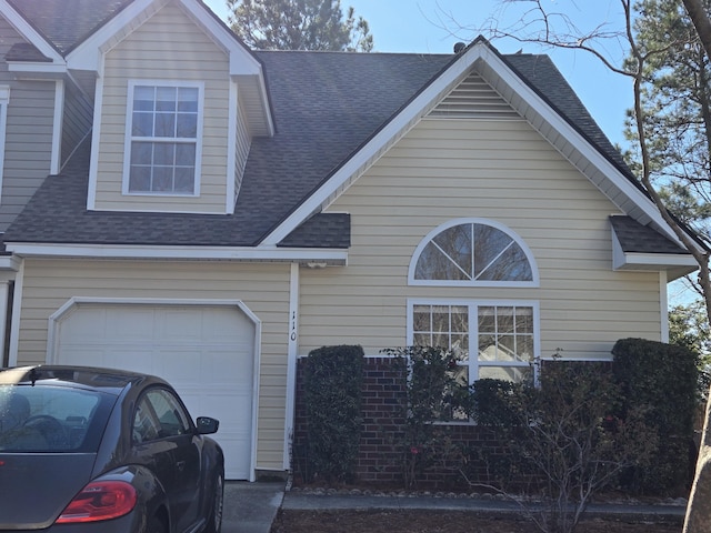 view of front of home with a shingled roof, brick siding, and a garage