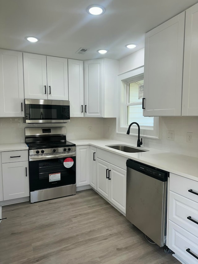 kitchen with sink, white cabinets, and appliances with stainless steel finishes