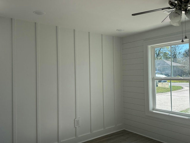 empty room featuring ceiling fan, dark hardwood / wood-style flooring, and wooden walls