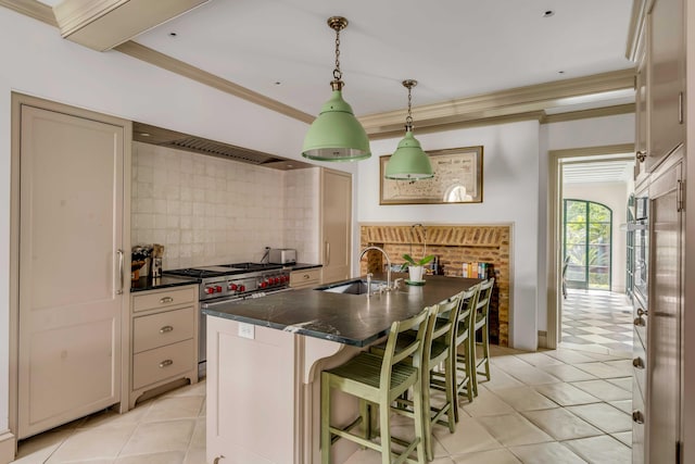 kitchen featuring a breakfast bar area, a center island with sink, pendant lighting, light tile patterned floors, and appliances with stainless steel finishes