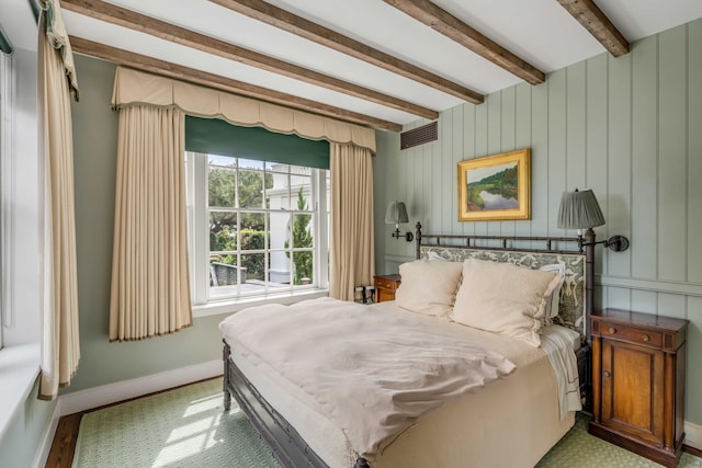 bedroom featuring beamed ceiling, wooden walls, and hardwood / wood-style flooring