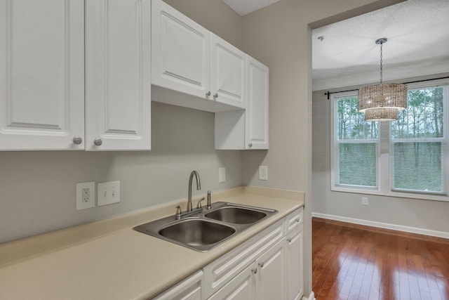 kitchen with white cabinetry, decorative light fixtures, sink, and dark wood-type flooring