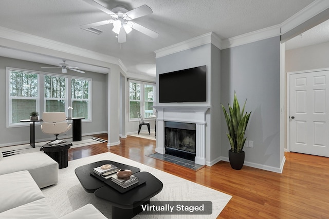 living room featuring crown molding, a fireplace, hardwood / wood-style floors, and a textured ceiling