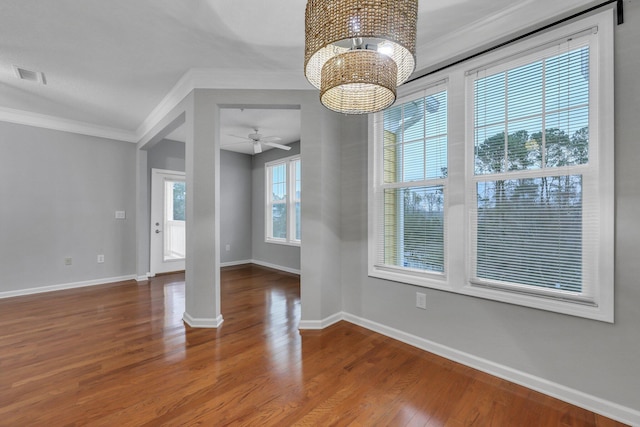 empty room with hardwood / wood-style floors, crown molding, and ceiling fan with notable chandelier