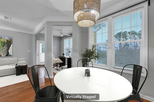 dining area with crown molding, wood-type flooring, and ceiling fan with notable chandelier