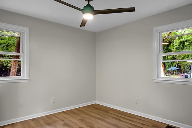 empty room with wood finished floors, baseboards, and ceiling fan