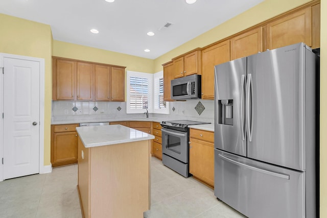 kitchen with decorative backsplash, a kitchen island, light tile patterned floors, and appliances with stainless steel finishes