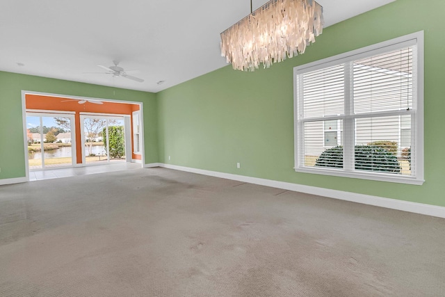 empty room featuring carpet, ceiling fan with notable chandelier, and a water view