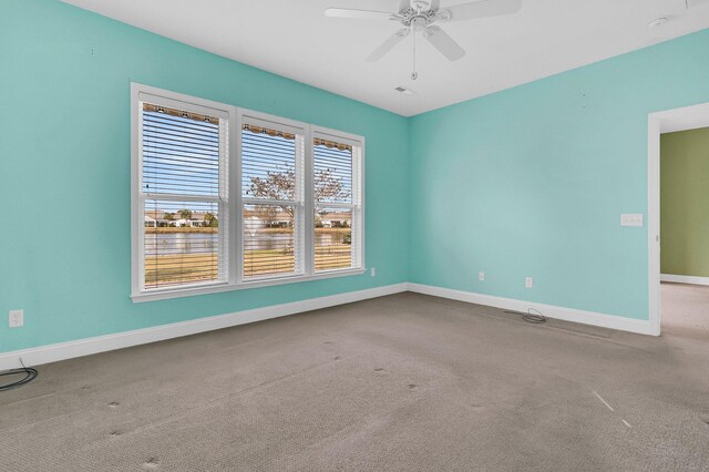 carpeted spare room featuring ceiling fan and a water view