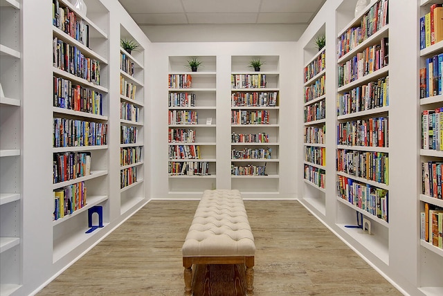 sitting room featuring built in shelves, light hardwood / wood-style flooring, and a drop ceiling