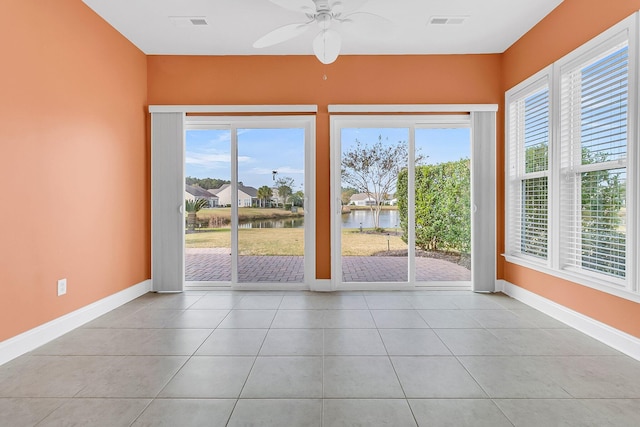 doorway to outside with ceiling fan, light tile patterned flooring, and a water view