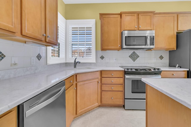 kitchen with light tile patterned flooring, appliances with stainless steel finishes, decorative backsplash, and sink