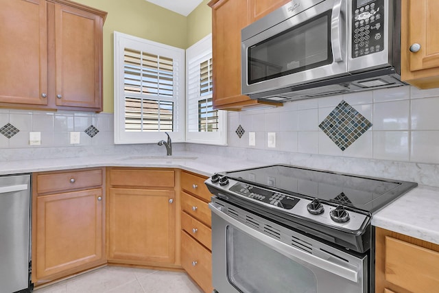 kitchen with decorative backsplash, sink, light tile patterned floors, and stainless steel appliances