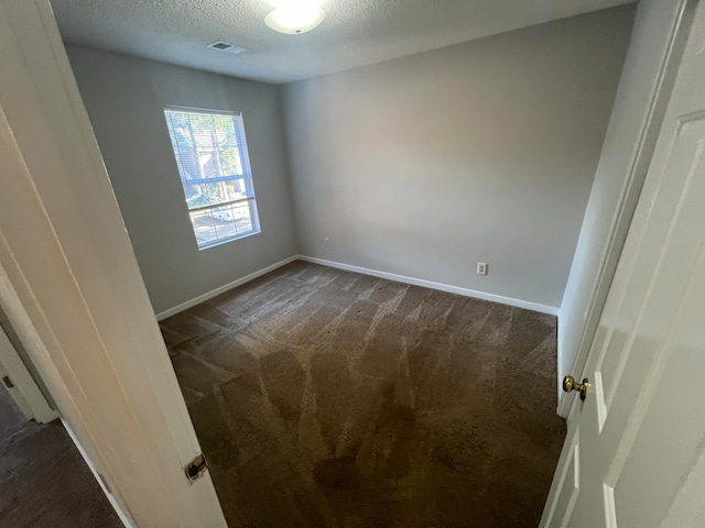 carpeted spare room with a textured ceiling