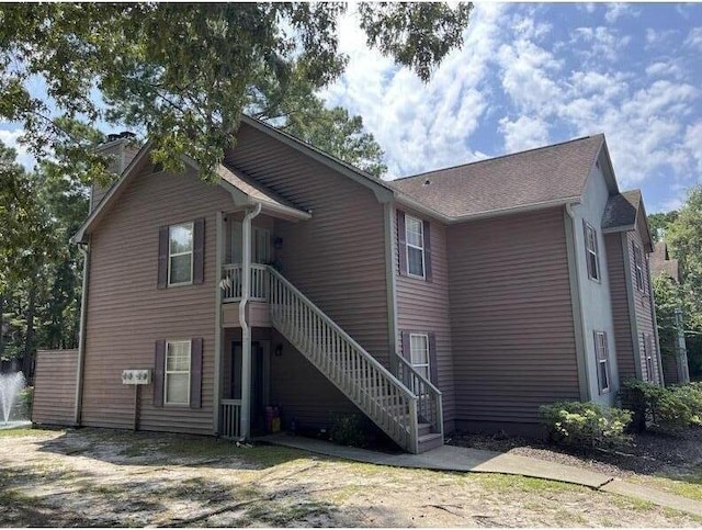 rear view of property featuring a chimney and stairway