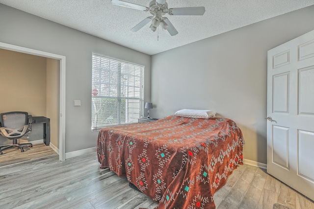 bedroom with a textured ceiling, light hardwood / wood-style floors, and ceiling fan