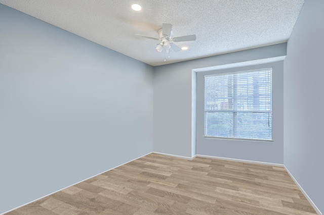 unfurnished room with ceiling fan, light wood-type flooring, and a textured ceiling