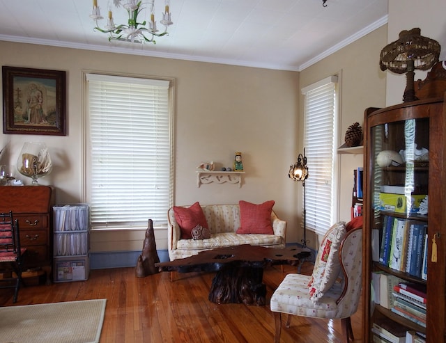 sitting room with a chandelier, wood-type flooring, and ornamental molding