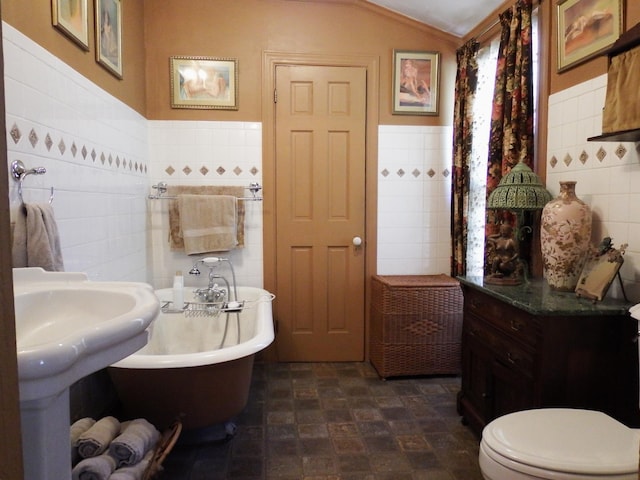 bathroom with lofted ceiling, a bathing tub, sink, toilet, and tile walls