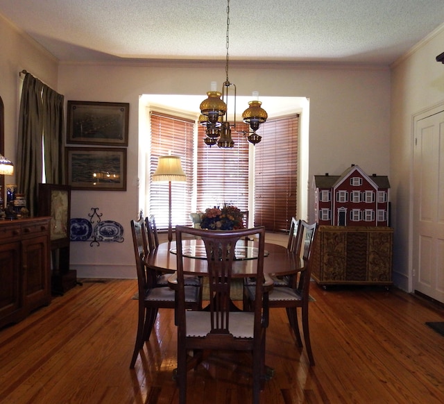 dining room featuring crown molding, dark hardwood / wood-style flooring, a textured ceiling, and an inviting chandelier