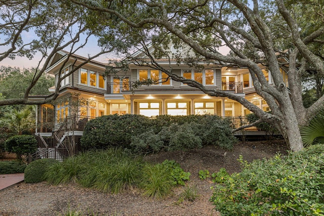 back house at dusk featuring a balcony