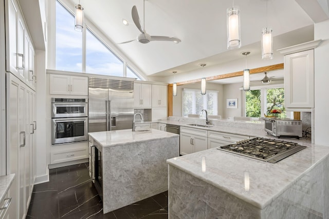 kitchen with light stone countertops, sink, kitchen peninsula, and white cabinets