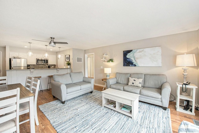 living area featuring a ceiling fan, visible vents, light wood-style floors, and baseboards