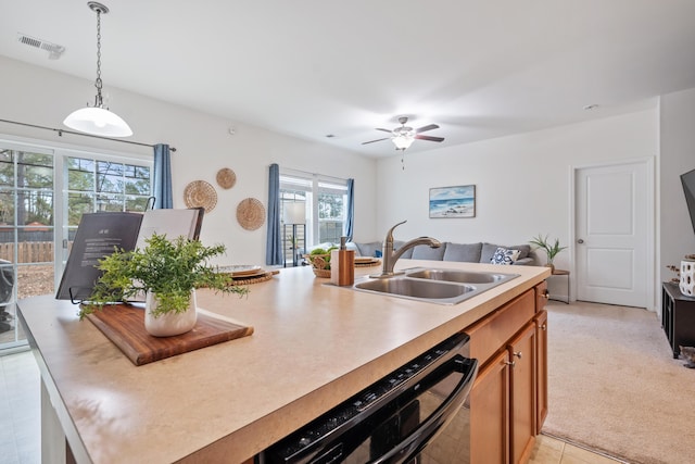 kitchen with decorative light fixtures, black dishwasher, sink, ceiling fan, and a center island with sink