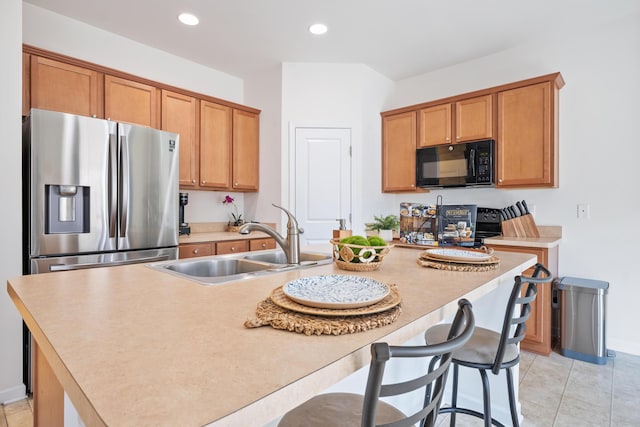 kitchen with a breakfast bar area, sink, a center island with sink, and black appliances