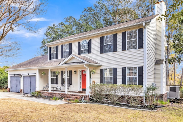 colonial home featuring a porch, central air condition unit, a front lawn, and a garage