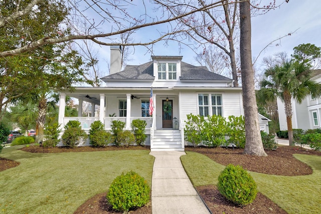 view of front of property featuring ceiling fan, a porch, a front lawn, and a chimney