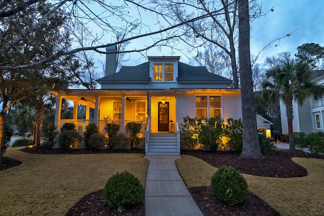 view of front of property with a chimney, a front lawn, a porch, and a ceiling fan