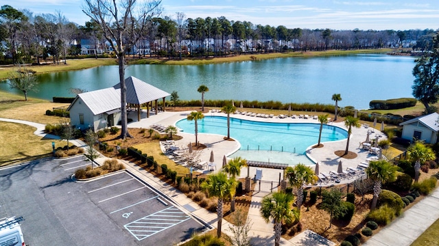 community pool with a water view, fence, and a patio