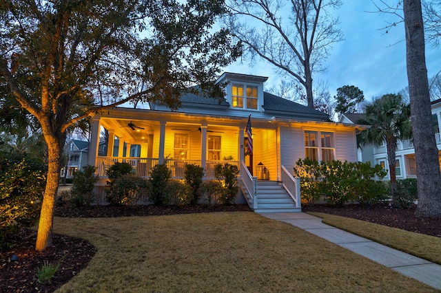 view of front of property with a ceiling fan, a porch, and a front lawn