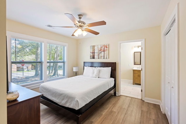 bedroom featuring ceiling fan, a closet, ensuite bath, and light hardwood / wood-style floors