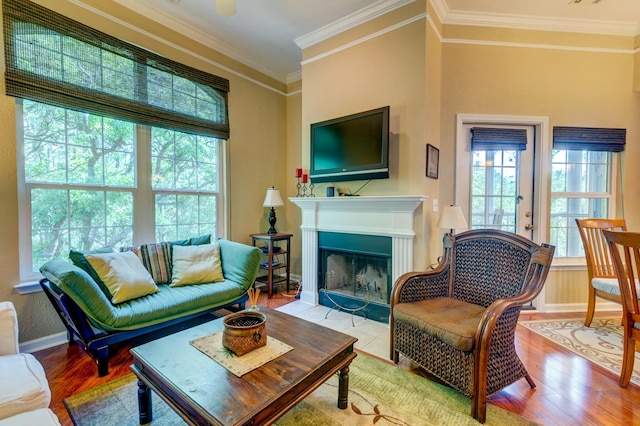 living room featuring a fireplace with flush hearth, wood finished floors, baseboards, and ornamental molding