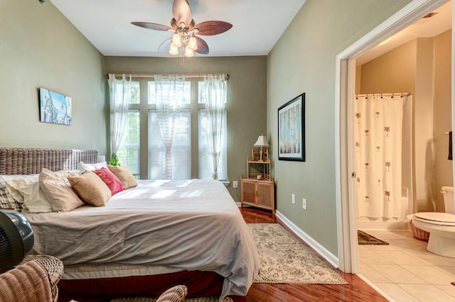 bedroom with wood finished floors, baseboards, connected bathroom, and ceiling fan