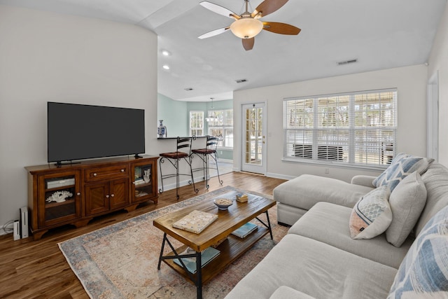 living area featuring ceiling fan, visible vents, vaulted ceiling, and wood finished floors