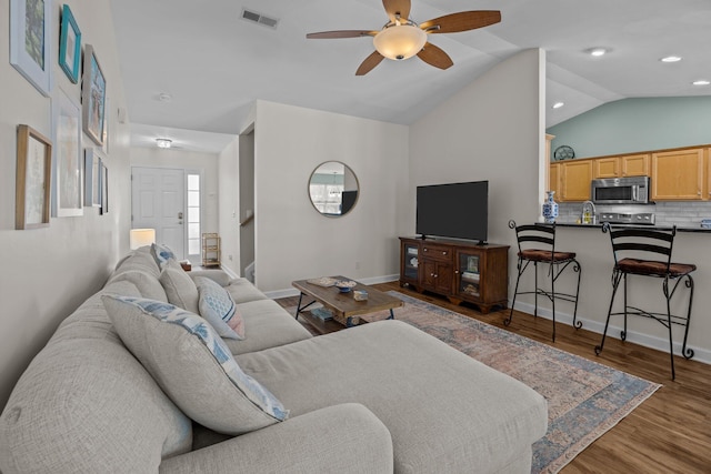 living area featuring baseboards, visible vents, lofted ceiling, ceiling fan, and wood finished floors