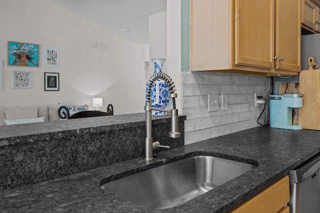 kitchen featuring dishwasher, dark stone counters, a sink, and decorative backsplash