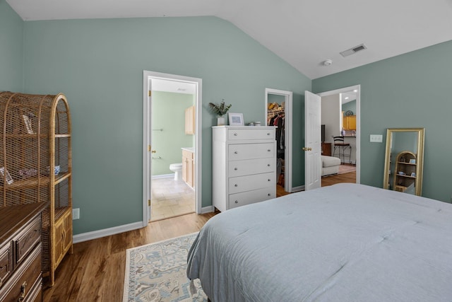 bedroom with lofted ceiling, a closet, visible vents, a spacious closet, and wood finished floors