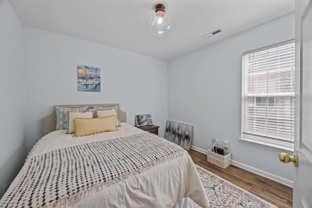 bedroom featuring visible vents, baseboards, and wood finished floors