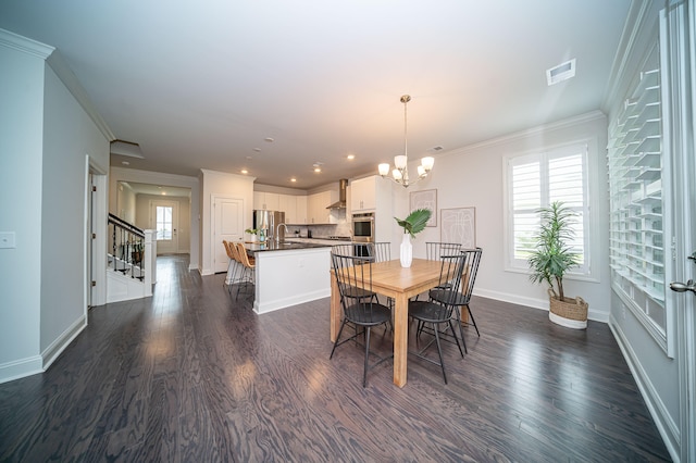 dining room featuring dark hardwood / wood-style flooring, a chandelier, crown molding, and sink