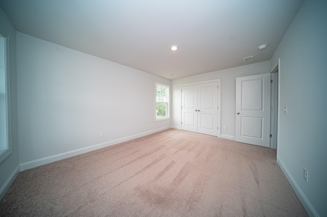 unfurnished bedroom featuring light colored carpet and a closet