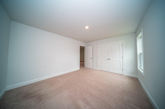 unfurnished bedroom with light carpet and a closet