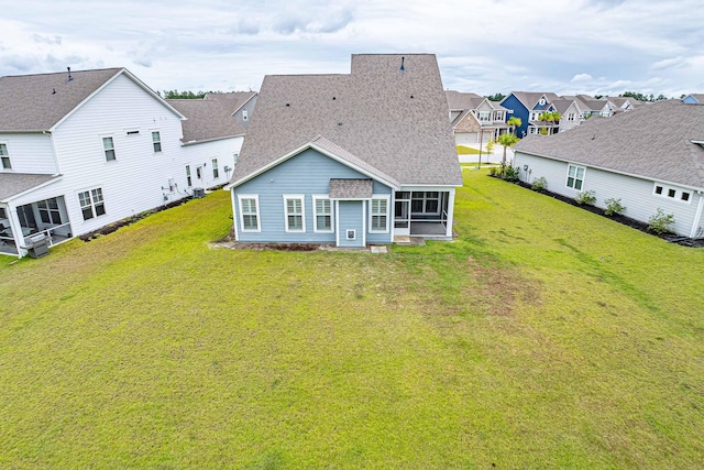 rear view of property with a lawn and a sunroom