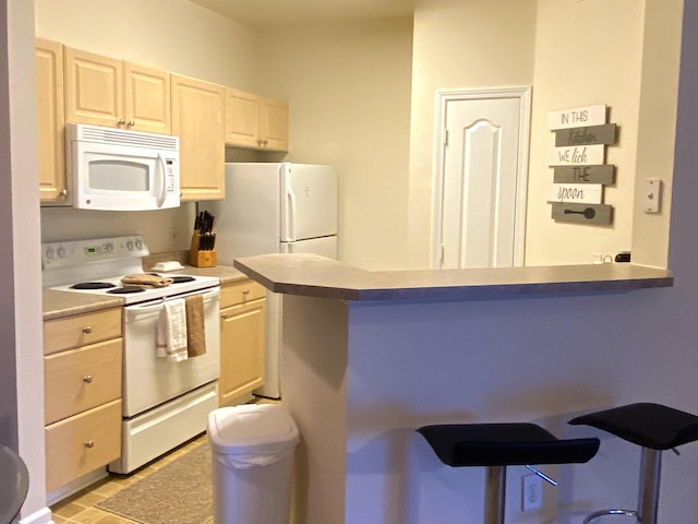 kitchen featuring white appliances, kitchen peninsula, and a breakfast bar area